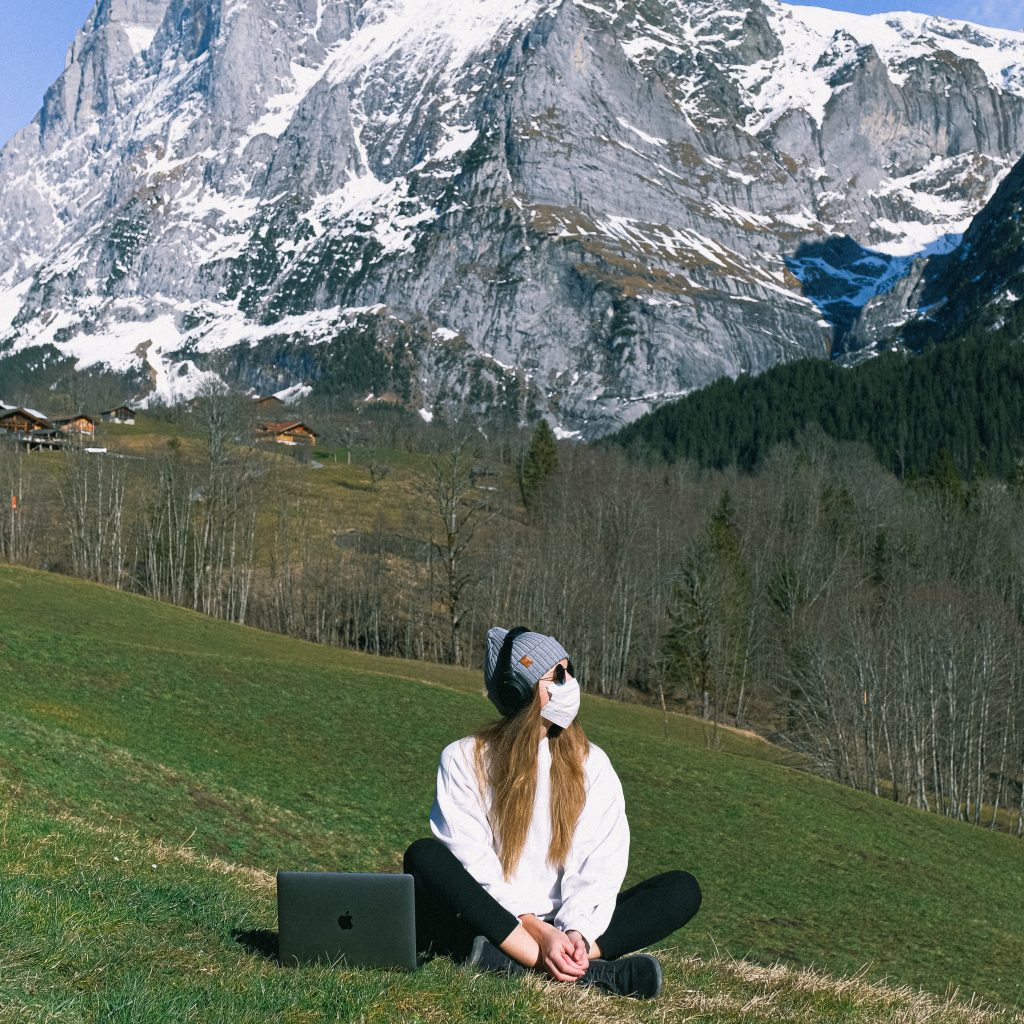 girl with mask doing chakra meditation by snowcapped mountains