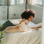 woman and dog reading on bed