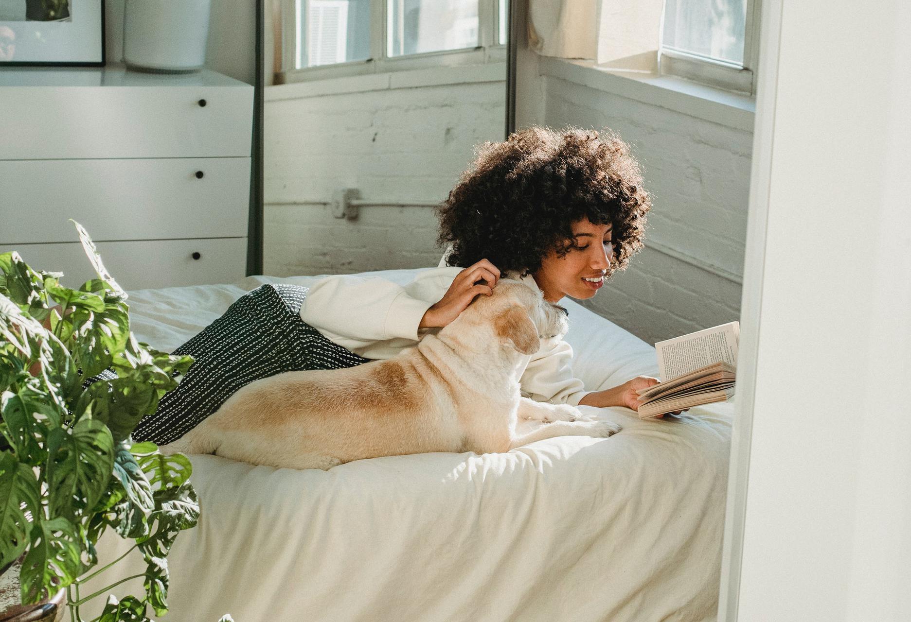 woman and dog reading on bed